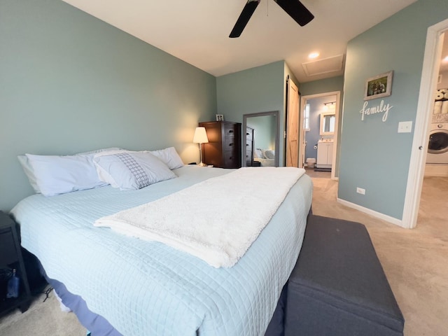 bedroom featuring baseboards, attic access, washer / clothes dryer, light colored carpet, and connected bathroom