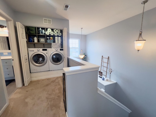 laundry area featuring washing machine and clothes dryer, visible vents, light colored carpet, and laundry area