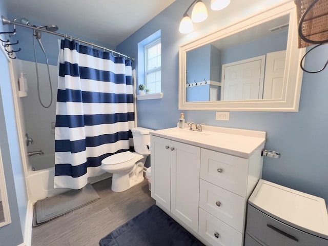 bathroom featuring vanity, wood finished floors, visible vents, shower / bath combo with shower curtain, and toilet