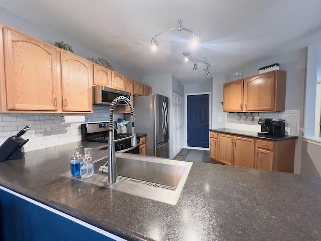 kitchen with decorative backsplash, dark countertops, appliances with stainless steel finishes, and a sink