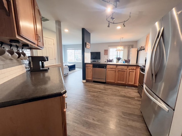 kitchen with visible vents, dark wood-style flooring, stainless steel appliances, dark countertops, and tasteful backsplash