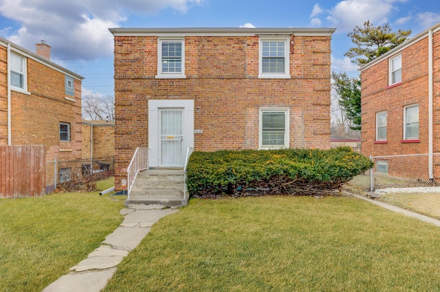 view of front facade with brick siding, fence, and a front lawn