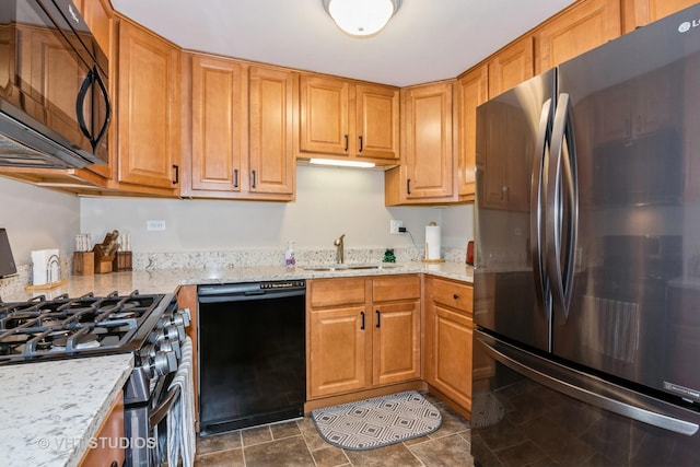 kitchen featuring light stone counters, brown cabinets, black appliances, and a sink