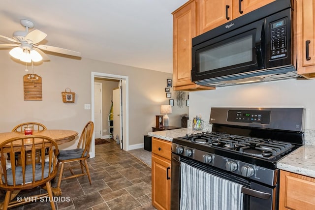 kitchen featuring baseboards, black microwave, light stone counters, stainless steel gas stove, and stone finish floor