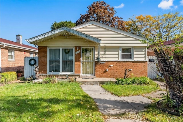 bungalow with brick siding, a front yard, and fence