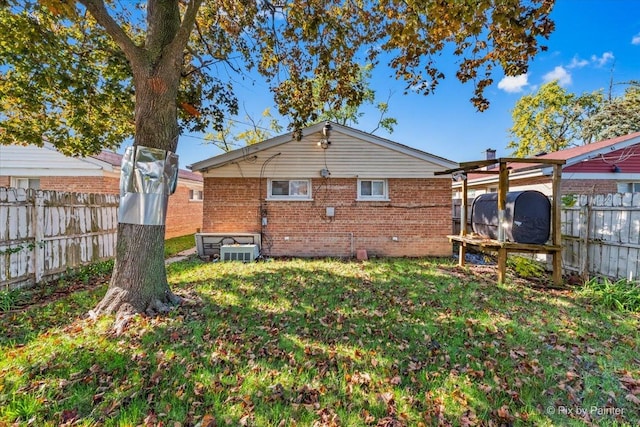 back of house featuring brick siding, fence, and a lawn