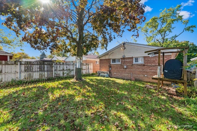 back of house with brick siding, a lawn, and fence