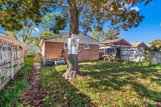 rear view of house with brick siding, a lawn, and a fenced backyard