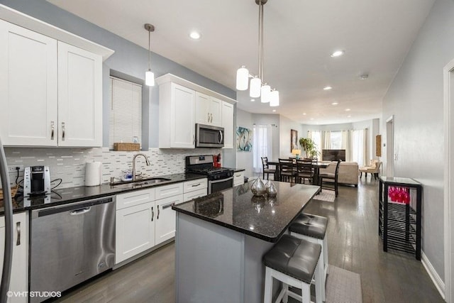 4904 W Fulton St, Chicago, IL 60644 - kitchen featuring appliances with stainless steel finishes, a sink, a breakfast bar, white cabinets, and recessed lighting