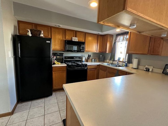 kitchen featuring brown cabinets, light tile patterned floors, light countertops, a sink, and black appliances