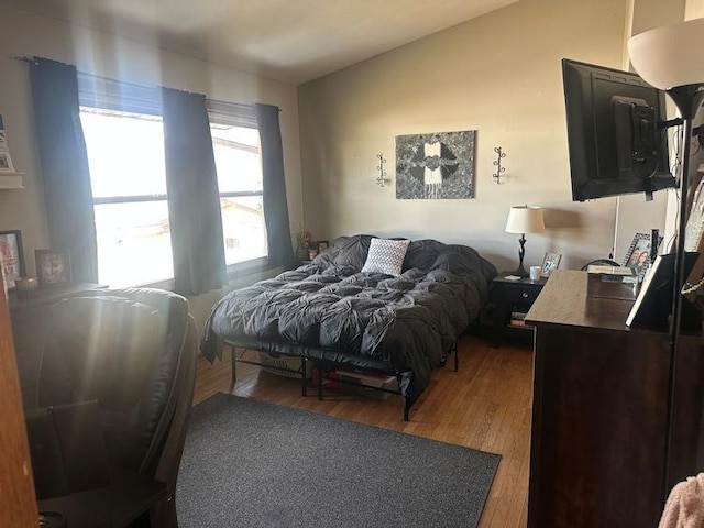 bedroom with vaulted ceiling and wood finished floors