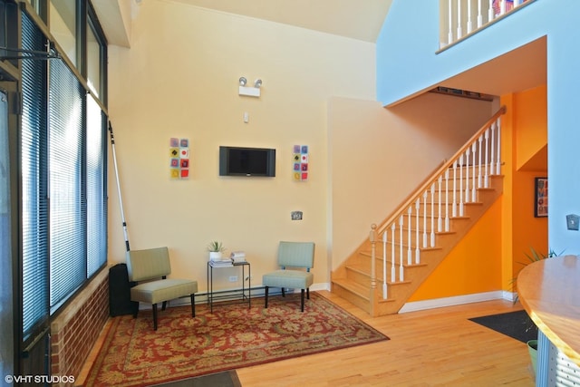 entryway with a towering ceiling, stairs, baseboards, and wood finished floors