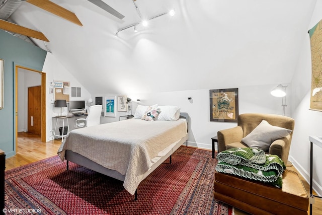 bedroom with track lighting, baseboards, vaulted ceiling, and wood finished floors