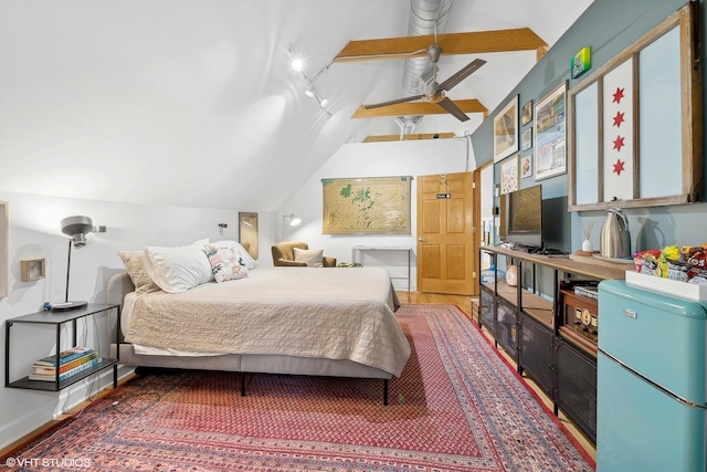 bedroom featuring lofted ceiling, fridge, wood finished floors, and track lighting