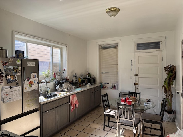 kitchen with light tile patterned floors, light countertops, a sink, and freestanding refrigerator