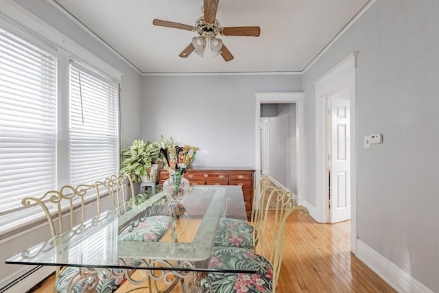 dining area with baseboards, ceiling fan, ornamental molding, baseboard heating, and light wood-style floors