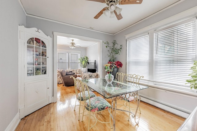 dining space with light wood-style floors, ceiling fan, ornamental molding, and baseboard heating