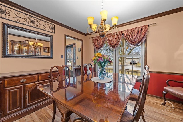 dining area featuring light wood-style floors, crown molding, and an inviting chandelier