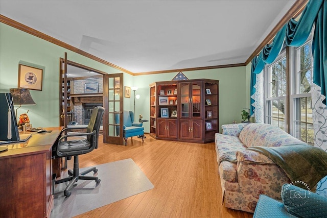 office with light wood finished floors, a brick fireplace, crown molding, and french doors