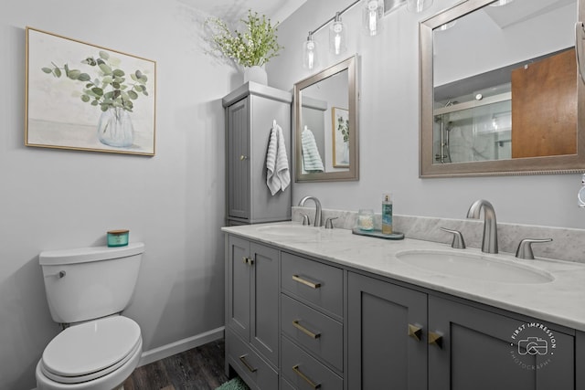 bathroom featuring toilet, baseboards, a sink, and wood finished floors