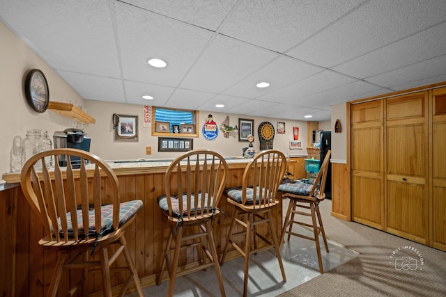 bar featuring a bar, a wainscoted wall, recessed lighting, and light colored carpet