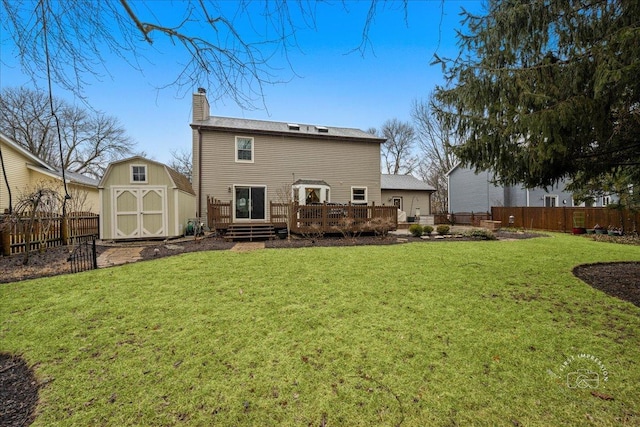 rear view of property featuring a chimney, a storage unit, a deck, a fenced backyard, and an outdoor structure