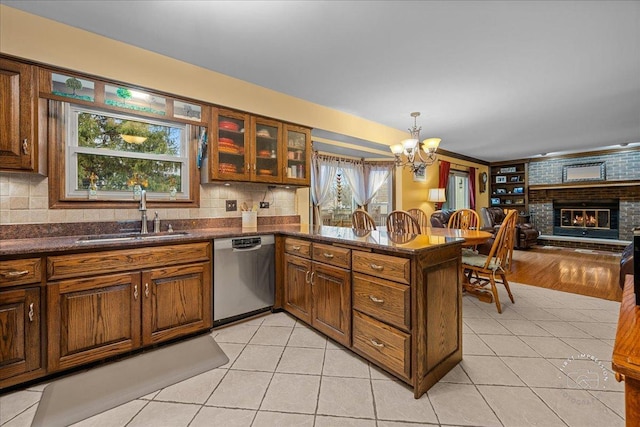 kitchen featuring a brick fireplace, a sink, stainless steel dishwasher, and light tile patterned floors