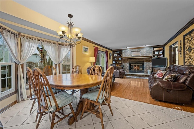 dining area with ornamental molding, a chandelier, light tile patterned flooring, and a fireplace