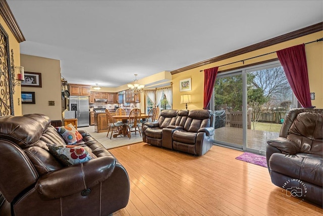 living room featuring ornamental molding, light wood finished floors, and a notable chandelier