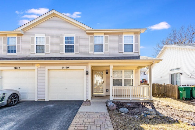 view of front of home with an attached garage, covered porch, driveway, and fence