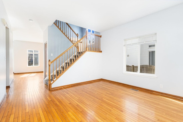 unfurnished living room with visible vents, baseboards, and hardwood / wood-style flooring