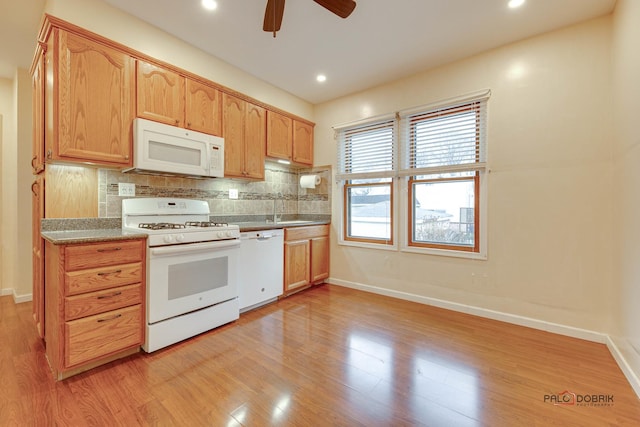 kitchen featuring a sink, white appliances, light wood-style flooring, and backsplash