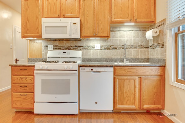 kitchen featuring tasteful backsplash, a sink, light wood-type flooring, white appliances, and baseboards