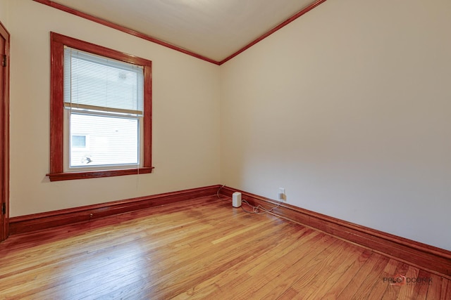 spare room featuring baseboards, ornamental molding, and light wood-style floors