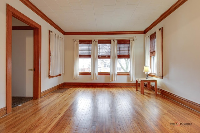 unfurnished room with baseboards, light wood-type flooring, and crown molding