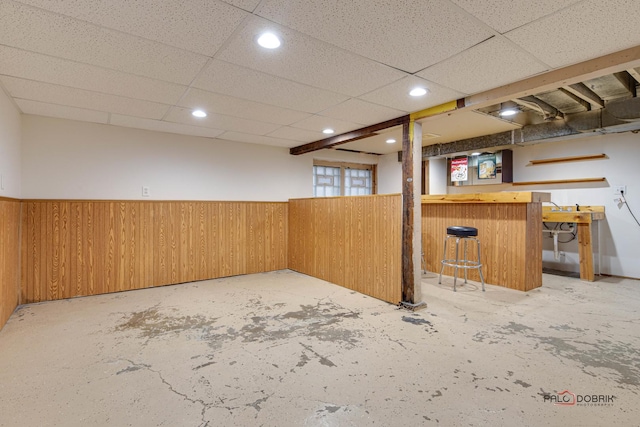 finished basement featuring a wainscoted wall, a dry bar, and wooden walls