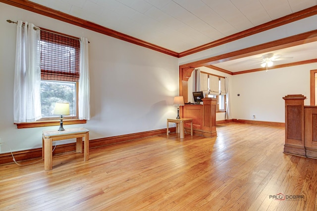 interior space with light wood finished floors, ceiling fan, baseboards, and crown molding