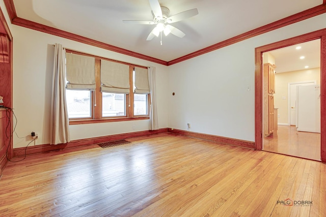 unfurnished room with light wood-style floors, visible vents, ornamental molding, and baseboards