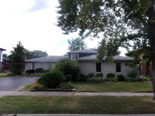 ranch-style house featuring driveway, brick siding, and a front yard