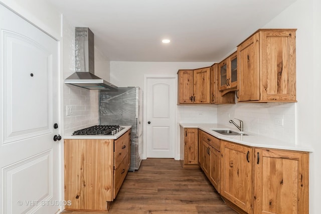 kitchen with dark wood finished floors, light countertops, a sink, gas cooktop, and wall chimney exhaust hood