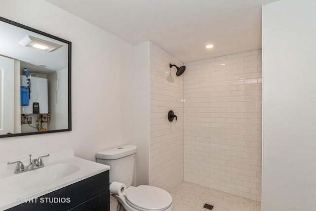 bathroom featuring toilet, tankless water heater, tiled shower, and vanity