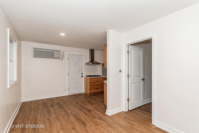 spare room with light wood-style floors, recessed lighting, an AC wall unit, and baseboards