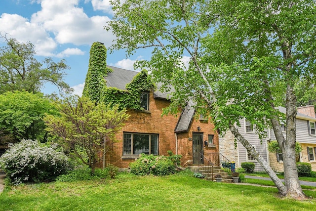english style home with a front yard and brick siding