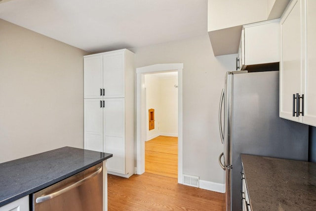 kitchen featuring light wood-type flooring, stainless steel appliances, white cabinets, and baseboards