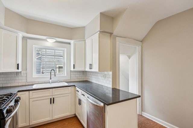 kitchen featuring a sink, dishwasher, dark countertops, gas stove, and tasteful backsplash