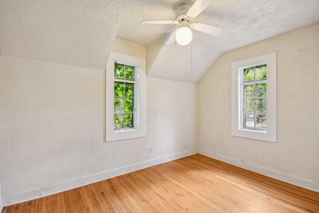 bonus room featuring baseboards, vaulted ceiling, healthy amount of natural light, wood finished floors, and a textured ceiling