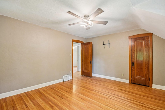 spare room featuring light wood-style flooring, a ceiling fan, vaulted ceiling, and baseboards