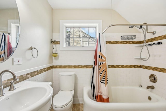 full bathroom featuring a sink, shower / tub combo with curtain, toilet, and tile walls