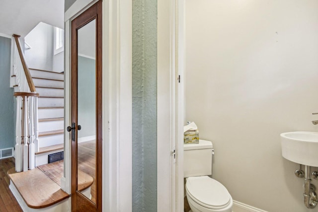 bathroom with baseboards, wood finished floors, and toilet