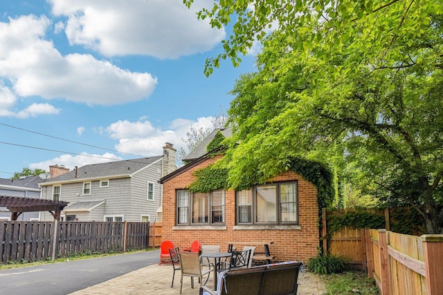 back of property featuring brick siding, a patio, and a fenced backyard